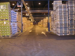 Inside Green Logistics Co., Kotka, Finland. The image shows goods loaded on pallets to the left of the aisle, and stacked pallets with no loads to the right of the aisle.